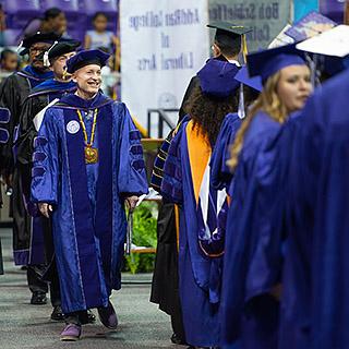 Chancellor Victor J. Boschini, Jr., in full academic regalia, leading a commencement processional of faculty